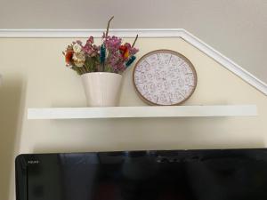 a white shelf with a clock and flowers on it at Terraza propia y baño privado in Santiago