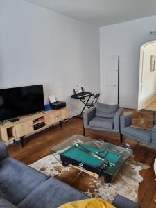 un soggiorno con divani, TV e tavolo di Maison de charme - accès autonome a Orléans
