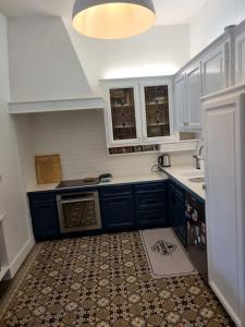 a kitchen with blue cabinets and a tile floor at Maison de charme - accès autonome in Orléans