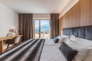 a bedroom with a bed and a desk and a window at Charming Suite by Dornsberg Panoramic Apartments in Schenna