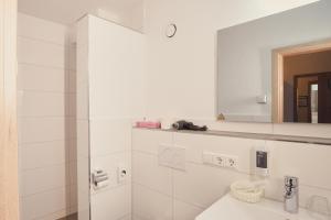 La salle de bains blanche est pourvue d'un lavabo et d'un miroir. dans l'établissement Landgasthaus Zollerstuben, à Bermatingen