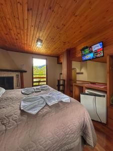 a bedroom with a bed with a tv on the wall at Hotel Pião Mineiro in Monte Verde