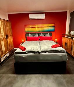 een slaapkamer met een groot bed met een rode muur bij Hafen Perle - Übernachtungen auf dem Wasser- Romantik & Wellness auf dem Rhein - in Leverkusen