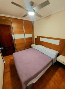 een slaapkamer met een paars bed en een plafondventilator bij GOLF DEL SUR ALBATROS 5 bed places apartment in San Miguel de Abona
