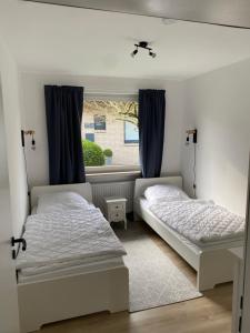 2 camas en una habitación con ventana en Gemütliches Ferienhaus in Küstennähe, en Wilhelmshaven