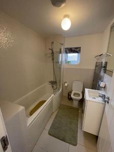 a bathroom with a tub and a toilet and a sink at Luxurious Five-Bedroom Haven in Long Stanton