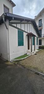 a white house with green doors and a yard at Maison Cosy in Lourdes +7 photos