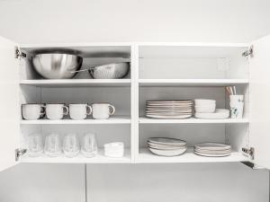 a white cabinet filled with dishes and plates at LIGHTPLACE • Moderne Innenstadt-Wohnung • Balkon zur Oker in Braunschweig