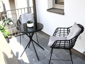 a black table and chairs on a balcony at LIGHTPLACE • Moderne Innenstadt-Wohnung • Balkon zur Oker in Braunschweig
