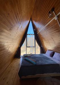 Bett in einem Holzzimmer mit einem großen Fenster in der Unterkunft Cottage "Sunset" in Batumi