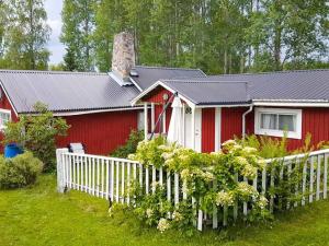 a red house with a white fence in front of it at Holiday home SÖDERALA in Söderala