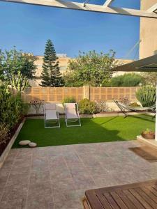 a patio with two chairs and a yard with grass at El Toyo Cactus in Almería