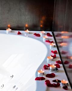 a row of candles in a bath tub with red roses at Rezidencija Grįžulo ratai in Sasnava