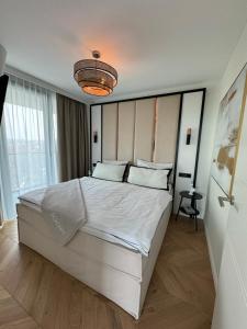 a bedroom with a large bed and a chandelier at Luxury Apartment Tyballtic 7th Floor in Międzyzdroje
