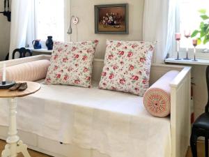 ein weißes Bett mit rosa Kissen und einem Tisch in der Unterkunft Holiday home NÄSSJÖ III in Nässjö