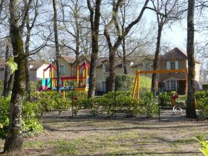 a playground in front of a house with trees at Charmant Appartement avec piscine. in Monflanquin