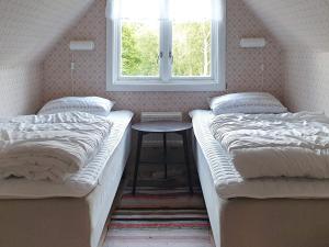 two beds in a room with a table and a window at Holiday home Annerstad in Skärseryd