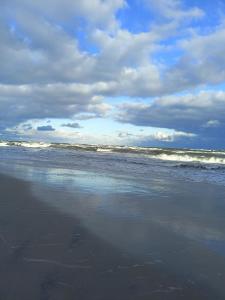 plaża z falami w oceanie w pochmurny dzień w obiekcie Domki apartamentowe BALIA w mieście Mieroszyno