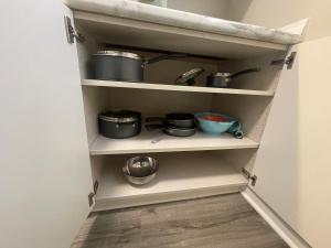 a kitchen pantry with pots and pans on shelves at Cute & Cozy Suite in Overland Park in Overland Park