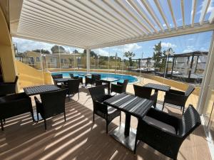 a patio with tables and chairs and a swimming pool at Quinta Nova Vale Del Rey in Carvoeiro