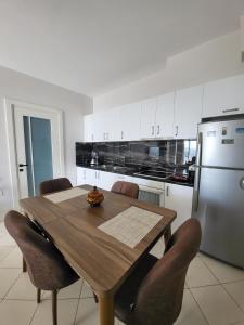 a kitchen with a wooden table with chairs and a refrigerator at Alex's Apartment 2 in Durrës
