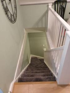 a stairway with a stair case and a clock on the wall at Honicombe Valley Lodge 23 Hot Tub Lodge in Gunnislake