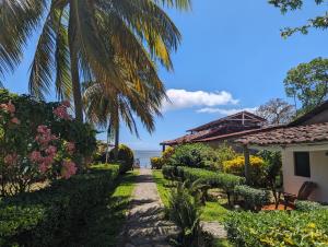 a path through a garden with the ocean in the background at Hotel Playa Santa Martha in Rivas