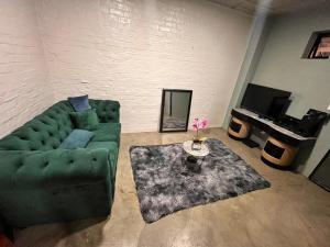 a living room with a green couch and a piano at Tina Guest Apartment in Johannesburg