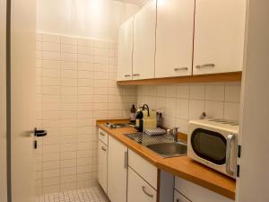 uma pequena cozinha com um lavatório e um micro-ondas em Top Lage - Bali-Appartment Hamburg em Hamburgo