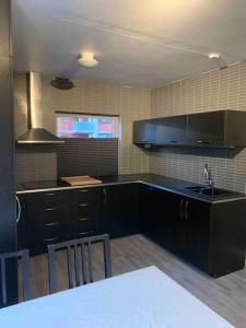 a kitchen with black cabinets and a sink and a table at Trivelig leilighet i Kristiansand sentrum! in Kristiansand