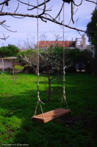 a wooden swing hanging from a tree in a yard at Garden house in Amarynthos