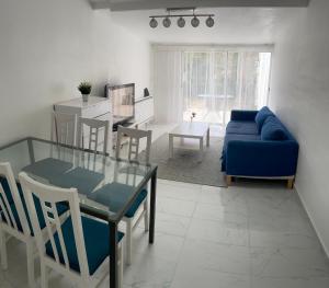 salon ze szklanym stołem i niebieską kanapą w obiekcie Maison indépendante 7 minutes RER B w mieście Antony