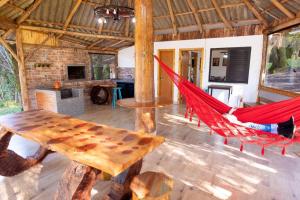 een kamer met 2 rode hangmatten en een tafel bij Cabana do Lago in Treze Tílias