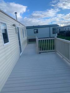 une grande terrasse en bois à côté d'une maison dans l'établissement A14 is a 3 bedroom caravan on Whitehouse Leisure park with large decking, à Abergele