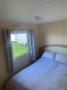 - une chambre avec un lit et une fenêtre dans l'établissement A14 is a 3 bedroom caravan on Whitehouse Leisure park with large decking, à Abergele