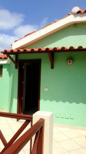 a green house with a door and a balcony at Residencial Ilha do Fogo app 205 in Santa Maria