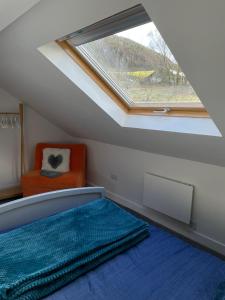 a attic room with a window and a bed and a chair at The Hayloft, Marsden in Huddersfield