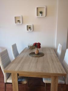 una mesa de comedor con sillas blancas y un jarrón con flores en CA LA VICKY en Deltebre