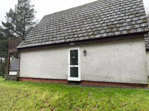 una casa blanca con una puerta verde y césped en Honicombe Valley lodge 25 en Gunnislake