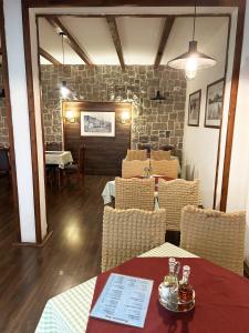 a restaurant with tables and chairs and a stone wall at Restaurant & Apartments JUG in Sutomore