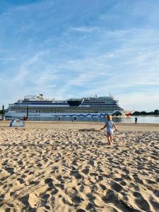 een kind dat op het strand loopt met een cruiseschip bij Top Lage - Bali-Appartment Hamburg in Hamburg