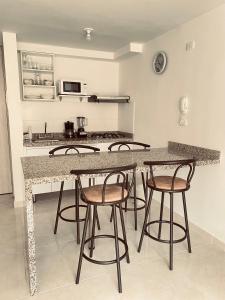 una cocina con 4 taburetes y una barra en Apartamento céntrico Plazuela, en Barranquilla