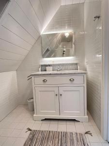 a white bathroom with a sink and a mirror at De Consistorie in Giethoorn