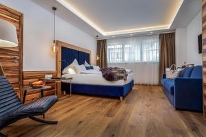 um quarto de hotel com uma cama e um sofá azul em Hotel Neuhaus em Saalbach Hinterglemm