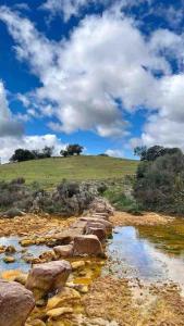 a field with a hill and a blue sky with clouds at Sierra de Huelva-Chalet completo in El Cerro de Andévalo