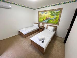 um quarto com duas camas e um quadro na parede em Afsana Hotel em Bukhara