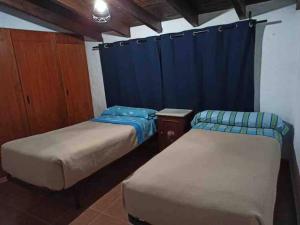 two beds in a room with a blue curtain at Sierra de Huelva-Chalet completo in El Cerro de Andévalo