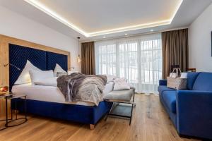 ein Schlafzimmer mit einem blauen Bett und einem blauen Sofa in der Unterkunft Hotel Neuhaus in Saalbach-Hinterglemm