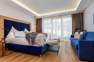 a bedroom with a blue bed and a blue couch at Hotel Neuhaus in Saalbach-Hinterglemm