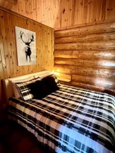 a bedroom with a bed in a wooden wall at Chalets Terre de L'Orme Chalet Bois Rond 2 in Saint-Gabriel-De-Valcartier